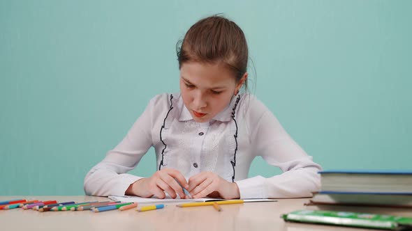 A Young Girl in a White Shirt at the Table Is Doing Homework