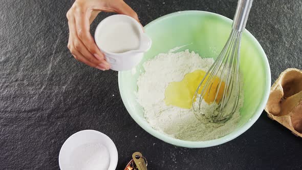 Woman mixing milk in flour 4k