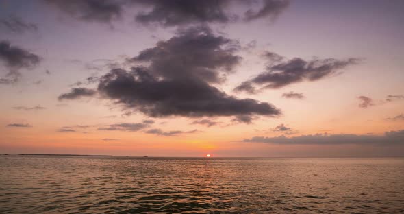 Time lapse: sunset over tropical sea colorful dramatic sky moving clouds. Kei Is