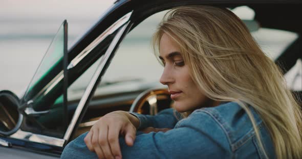 Beautiful woman in a vintage car at sunset