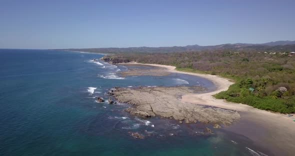 Aerial drone view of the beach, rocks and tide pools in Playa Palada, Guiones, Nosara, Costa Rica.