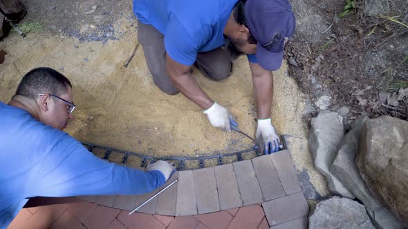 Overhead shot of curving brick paving focus on the black edge retainer which is held into place by a