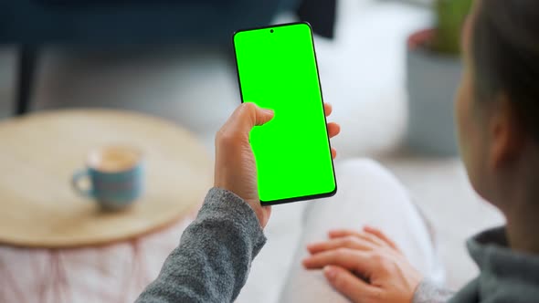 Woman at Home Using Smartphone with Green Mockup Screen in Vertical Mode