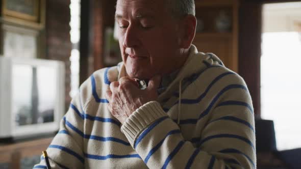 Senior man writing in a book at home