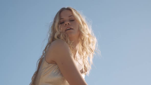 Woman Dancing In Gold Dress Under Blue Sky