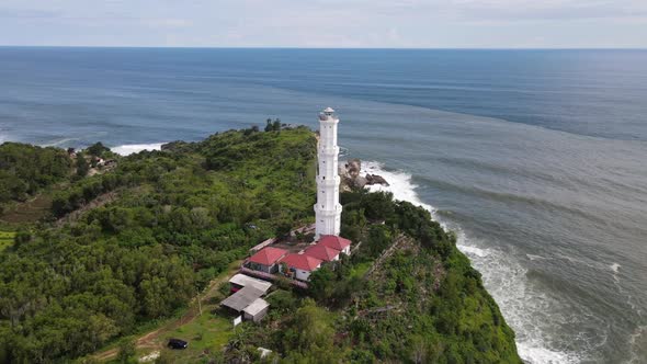 Aerial view of Baron Beach in Gunung Kidul, Indonesia with lighthouse and traditional boat.