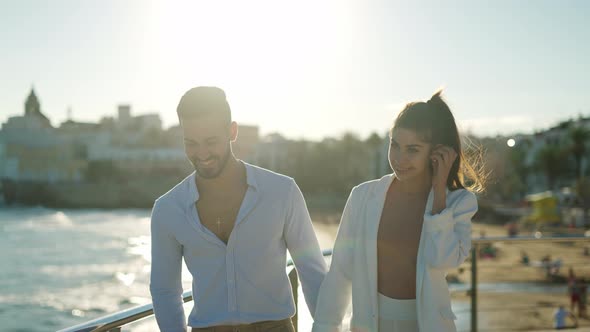 Hispanic Couple Walking and Talking Against Sea in Town