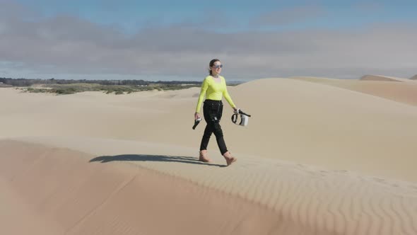 Beautiful Woman in Neon Futuristic Costume and VR Glasses Walking By Sand Dunes