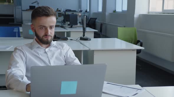 Overworked Bearded Man Sits and Looks on the Computer