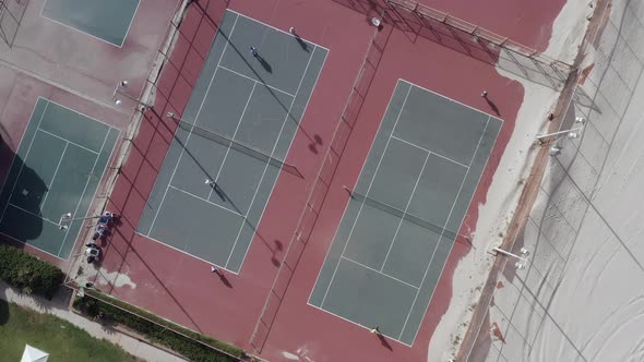 Two Tennis players enjoying a tennis match on the beach, with sand covering the court corner.