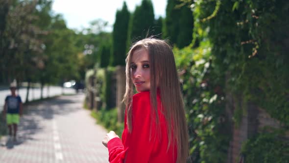 Attractive girl outdoors in summer. Long-haired woman in passionate red dress looking on camera