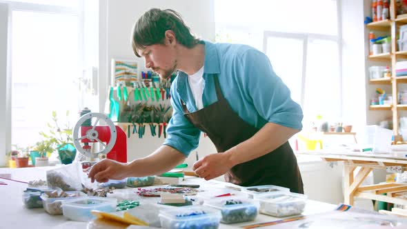 Young man with mosaic in workshop. Young master in an apron at work