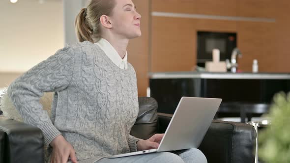 Young Woman with Back Pain Working on Laptop at Home 