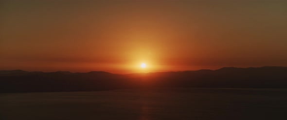 Beautiful landscape with sunset over the big lake and the mountains. Panning left shot. 