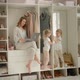 Mom with a Laptop Sits on the Closet and the Twin Daughters Play on the Closet - VideoHive Item for Sale