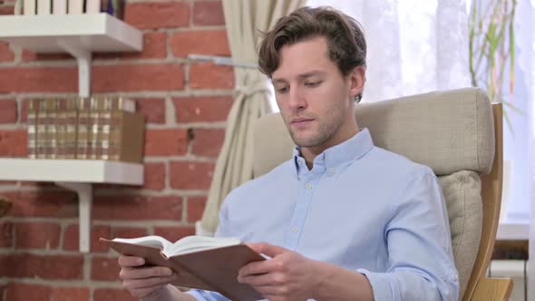 Focused Young Man Reading a Book in Office