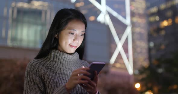 Woman working on smart phone at night