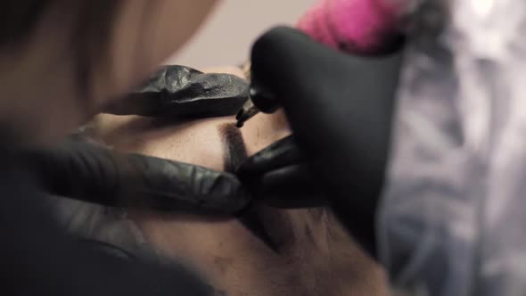 Professional Tattoo Master Applying Permanent Make-up of Eyebrows