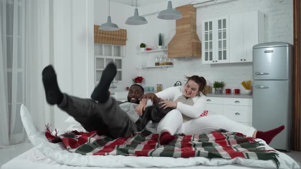 Joyful Multiracial Couple Fooling Around on Bed