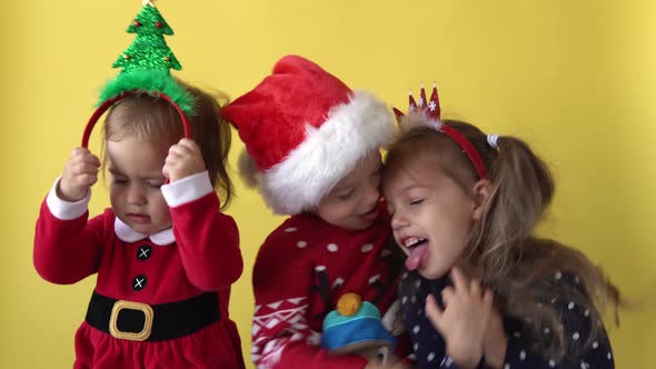 Emotion Cute Happy 3 Siblings Friends Baby Girl Boy Kissing Hug In Santa Suit Looking On Camera At