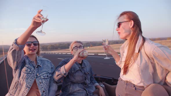 Group of Happy Friends in a Cabriolet and Drinking Campagne - Young People Applauding and Having Fun