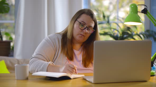 Overweight Young Woman Working Online with Laptop Computer at Home Office Having Video Conference