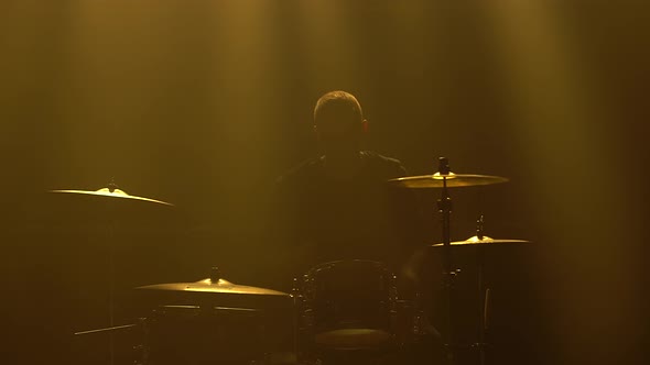 Silhouette Drummer Playing on Drum Kit on Stage in a Dark Studio with Smoke and Neon Lighting