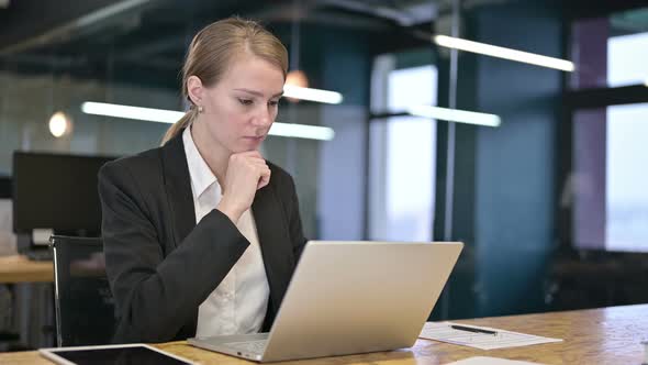 Young Businesswoman Thinking and Working on Laptop in Office