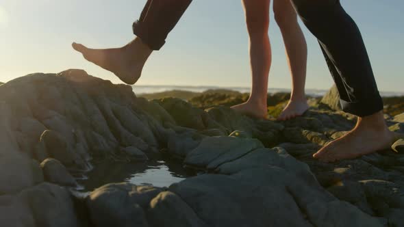 Low section of couple walking on rock at the beach 4k