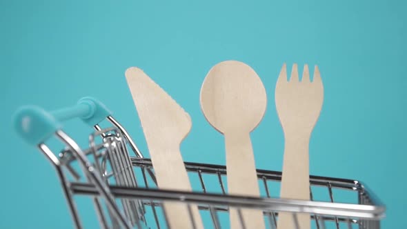 Wooden disposable recycled kitchen utensils in a small shopping cart