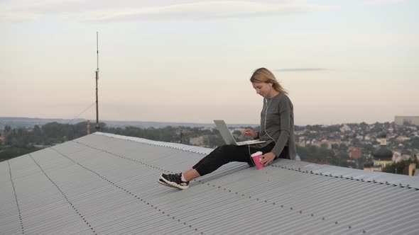 Woman on the rooftop, with laptop and coffee cup