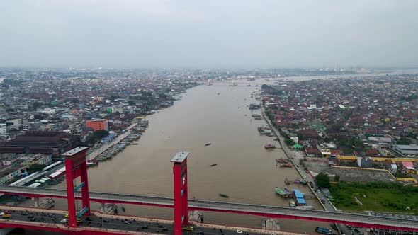 Red color bridge pf Ampera over Musi river with cityscape of Palembang, aerial view
