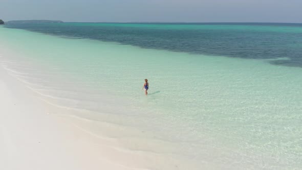 Aerial: Woman on white sand beach turquoise water tropical coastline caribbean sea