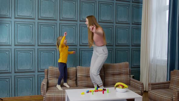 Happy Funny Family Mother and Child Kid Daughter Dancing Jumping on Sofa Listening Music at Home