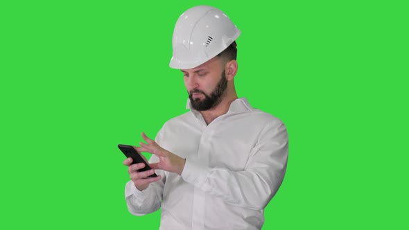 Smart Engineer in White Shirt and Safety Engineering Hat Using Smartphone on a Green Screen, Chroma