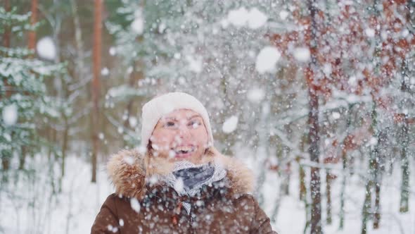 Winter Fun Outside Woman Throwing Snow in the Air and Smiling