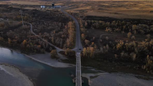 Aerial footage of an old truss bridge over old man river in Alberta, Canada during autumn. Dark fore