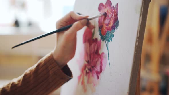 Close-up Shot of Female Hand Holding Paintbrush and Painting Bright Flowers on Canvas in Light