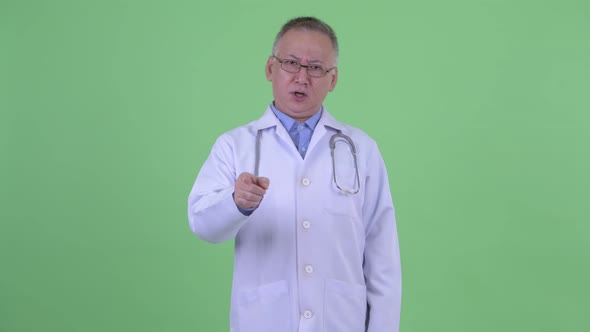 Happy Mature Japanese Man Doctor Laughing and Pointing at Camera