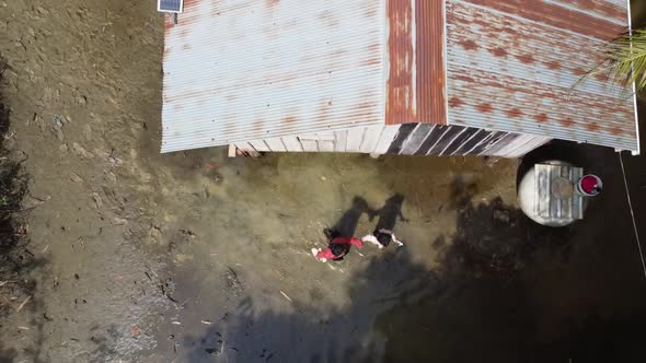 Aerial top down shot showing woman and daughter leaving flooded homestead in Cambodia.