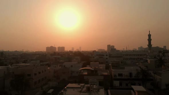 Aerial Over Of Karachi Skyline With Mosque Minaret Against Golden Orange Sunset. Pedestal Up