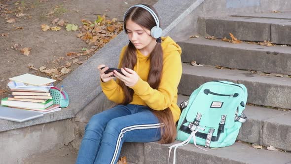 A Teenage Girl in Headphones Seriously Looks Into the Smartphone Screen Online Learning