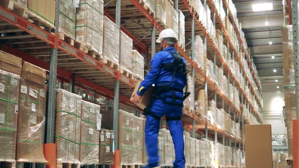 Storage Employee is Using Ergoskeleton to Carry the Boxes