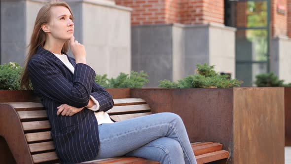 Pensive Businesswoman Thinking while Sitting Outside Office on Bench