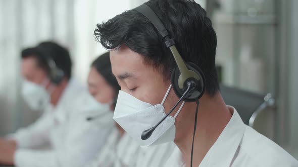 Close Up Of An Asian Man Call Centre Agent Wearing Mask While Speaking To Customer
