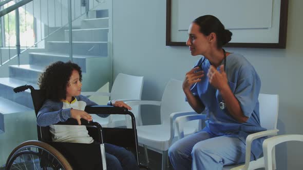 Front view of Caucasian female doctor interacting with disabled boy in the corridor at hospital 