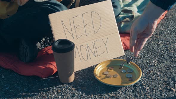 Coins are Getting Thrown Into Beggar's Plate