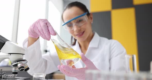 Scientist Examines Yellow Transparent Liquid in Flask