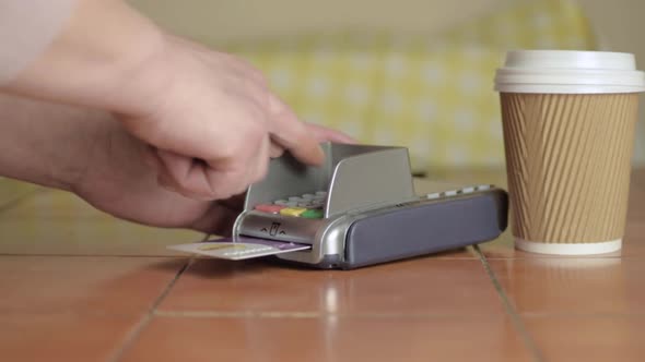 Hand paying by card with take out coffee cup medium shot