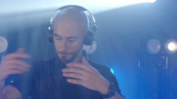 Live DJ Performance of Energetic Bald Man with Headphones Dancing on Party Concert Musician Stage